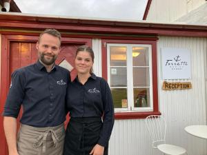 a man and woman standing in front of a restaurant at Berunes HI Hostel in Berunes