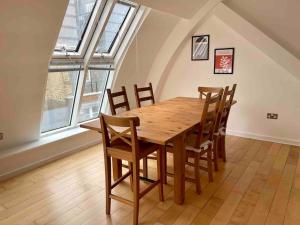 einen Holztisch und Stühle in einem Zimmer mit Fenstern in der Unterkunft Shad Thames by condokeeper in London