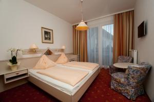a bedroom with a bed and a table and a chair at Pension & Apartments Ertl in Seeboden