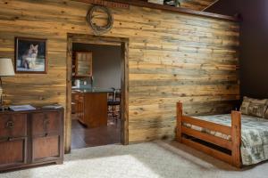 1 dormitorio con pared de madera, cama y escritorio en Large home less than 5 miles to Yellowstone North Entrance, Sleeps up to 8 en Gardiner