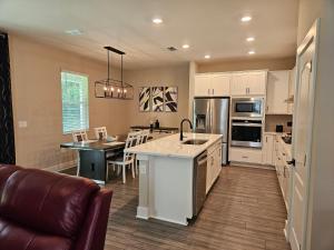 uma cozinha com armários brancos, uma mesa e um sofá em Endearing Private Bedroom in Shared House in Reunion Resort em Kissimmee