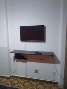 einen Flachbild-TV an einer Wand mit einem Schreibtisch in der Unterkunft Apartamento de frente a Praia, pé na areia com wi-fi LOFTJM com 01 vaga de garagem sujeita a disponibilidade in Santos
