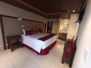 um quarto com uma grande cama branca com almofadas vermelhas em HOTEL Y RESTAURANTE HACIENDA LOS VOLCANES em Santa Lucía Milpas Altas