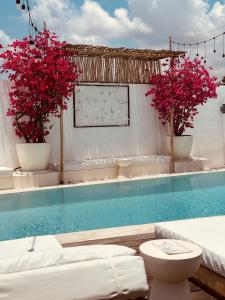 a swimming pool with two potted pink flowers in buckets at Love Song Boutique Hotel in Canggu