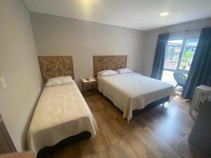 1 dormitorio con 2 camas y ventana en LOS LIRIOS en Puerto Iguazú