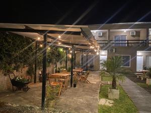 une terrasse avec des tables et des chaises sous une pergola la nuit dans l'établissement LOS LIRIOS, à Puerto Iguazú