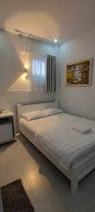 a white bedroom with a bed and a window at Vy Khanh Guesthouse in Ho Chi Minh City