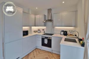 una cocina con armarios blancos y fregadero en Newly-Built Urban Retreat by TTLG Stays en Rickmansworth