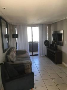 a living room with a couch and a television at Apartamento MOBILIADO 200m do mar com vista mar, garagem, ar condicionado in Fortaleza