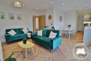a living room with two green couches and a kitchen at Modern City Escape by TTLG Stays in Rickmansworth