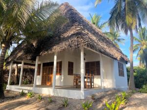 a cottage on the beach with palm trees at Jumapili Beach Villa in Ushongo Mabaoni