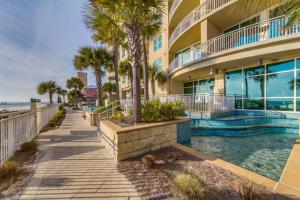 a building with a swimming pool and palm trees at AQUA 1504 Beachfront condo with Free Beach Chairs in Panama City Beach