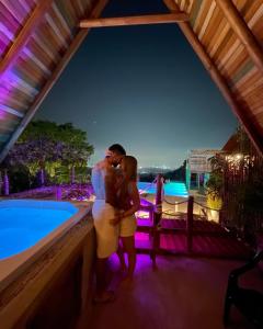 a couple kissing in front of a swimming pool at night at ADA MARINA - 3 acomodaciones con jacuzzi, malla y vista a Cartagena, 1 acomodacion con jacuzzi escondido, zona social con piscina infinita in Turbaco