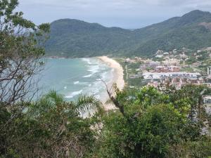 Blick auf einen Strand mit Stadt und Berge in der Unterkunft Apartamento 50 metros do Mar da Brava Floripa in Florianópolis