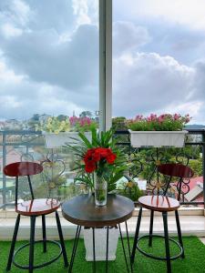 Cloud River Homestay في دالات: شرفة مع كرسيين وطاولة مع إناء من الزهور