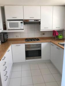 a kitchen with white cabinets and a stove and microwave at SAN ALFONSO DEL MAR HERMOSA VISTA A LA BAHIA 4D/3B in Algarrobo