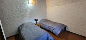 a room with two beds and a wall at Departamento Erlich in Godoy Cruz