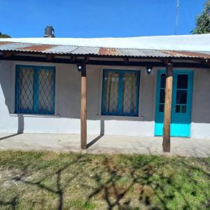 ein Haus mit blauen Fenstern und einem Dach in der Unterkunft Alquileres de la sierras gde in Tandil