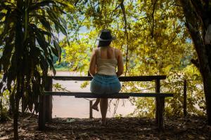 a woman in a hat sitting on a bench at K'erenda Homet Reserva Natural in Puerto Maldonado