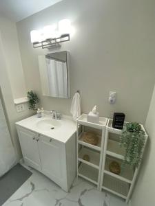 Baño blanco con lavabo y espejo en Boston 2bd- Walk to Harvard, MIT, subway Parking, en Somerville