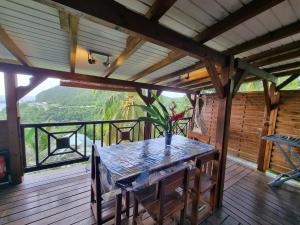 a wooden porch with a table on a deck at Lodge grenadine in Deshaies