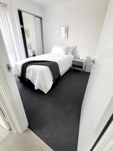 a white bedroom with a bed and a window at Comfort oasis family getaway in Henley Brook