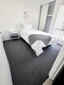 a white bedroom with a bed and a table at Comfort oasis family getaway in Henley Brook
