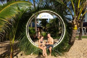 a man and woman sitting in a circular mirror on the beach at Sea Star Resort in Phú Quốc