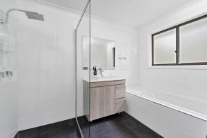 une salle de bain blanche avec une douche et un lavabo dans l'établissement Sandals at the Bay Upstairs sleeps 6 Hyams Beach, à Hyams Beach 15 autres photos