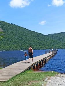 a man and a child walking on a dock at Dunas Tiny House Casa 2 in Florianópolis