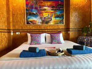 Un dormitorio con una cama con almohadas azules y una pintura en Deep House Sea View, en Ko Lanta