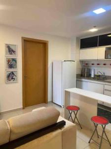 a kitchen with a couch and two stools in a room at APT Perfeito, duas suítes no shopping Dfplaza in Brasilia