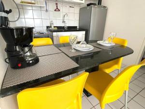 cocina con mesa y sillas amarillas en Costa Dourada, en São José da Coroa Grande