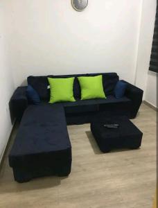 a black couch with green pillows in a living room at Ajay's residence in Hanya