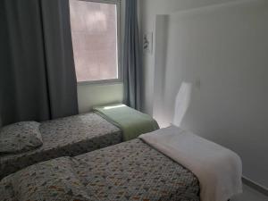 a small bedroom with two beds and a window at APT Perfeito, duas suítes no shopping Dfplaza in Brasilia