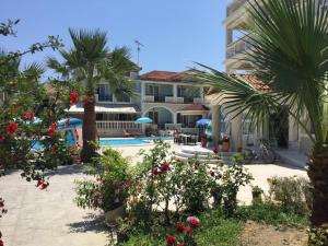 a resort with a pool and palm trees and flowers at Hotel Villa Basil in Tsilivi