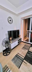 a living room with a television and a clock on the wall at 1BR Condo Unit at Celandine Condominium Near Ayala Cloverleaf Mall in Manila