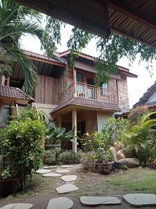 a garden in front of a house with a balcony at Little Elephant Cottage in Gili Trawangan