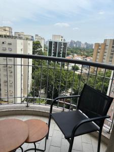 a balcony with a chair and table and a view of a city at Flat no Itaim in São Paulo