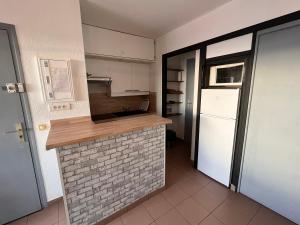 a kitchen with a brick counter and a refrigerator at Un printemps face au lac marin in Le Barcarès