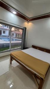 a bedroom with a bed and a large window at Mohor Retreat in Alibag