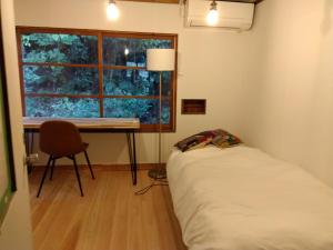 a bedroom with a bed and a desk and a window at 朝食付き唐津里山の宿&ヨガ兎と亀 in Karatsu