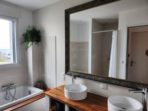 La salle de bains est pourvue d'un lavabo et d'un grand miroir. dans l'établissement Maison Vue Mer, à Pornichet
