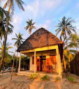 una pequeña casa en la playa con palmeras en Jumamosi Beach Villa en Ushongo Mabaoni