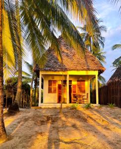 mały domek z palmą przed nim w obiekcie Jumamosi Beach Villa w mieście Ushongo Mabaoni