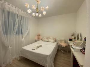 a white bedroom with a bed and a chandelier at Conforto na Praia do Pontal in Rio de Janeiro