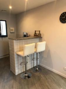 a bar with two white stools in a kitchen at Jolie petite maison cosy in Orly