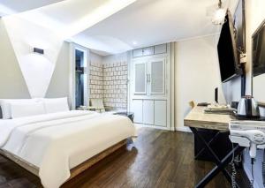Schlafzimmer mit einem großen weißen Bett und einem Schreibtisch in der Unterkunft 24 Block Hotel in Suwon