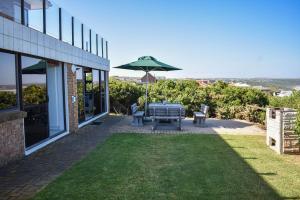 a backyard with a grill and an umbrella at Sea Gem with a stunning view in Boggomsbaai