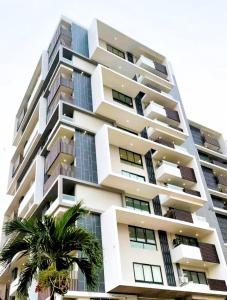 阿克拉的住宿－Spacious Executive Luxury Apartment，一座高大的建筑,前面有一棵棕榈树
